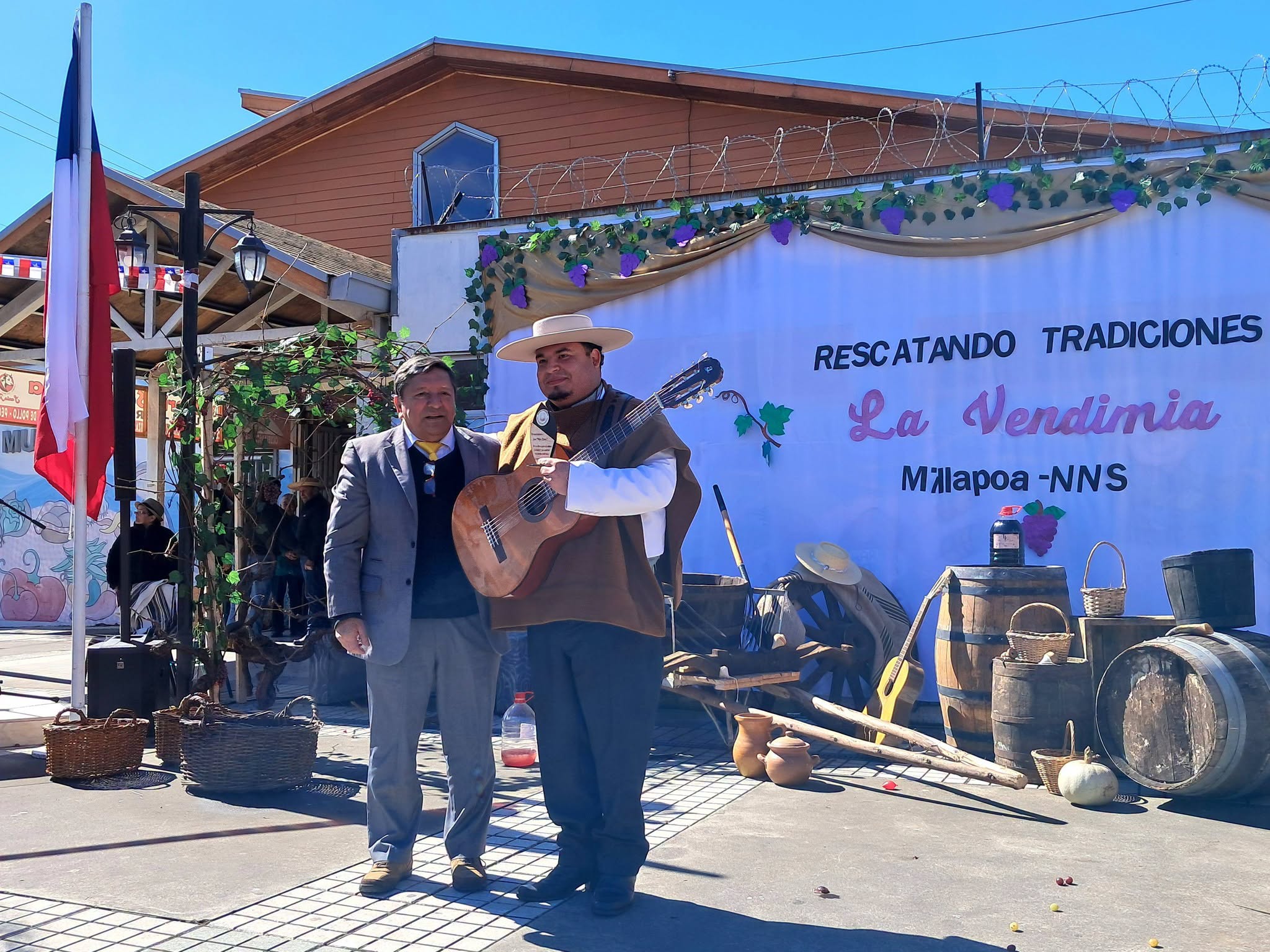 Pepe Flores sostiene su distinción junto al inspector general Abdón Muñoz, frente a la escenografía de la vendimia.