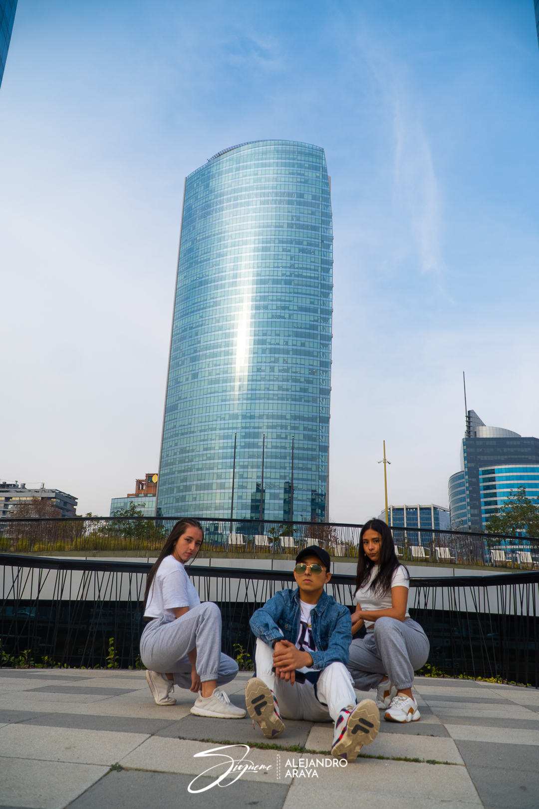 Alejandro Araya y dos bailarinas posan al aire libre junto a edificios de Santiago, en una imagen de «Sígueme».
